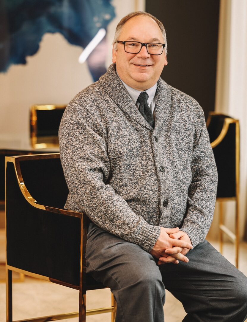 a man wearing a suit and tie sitting in a chair