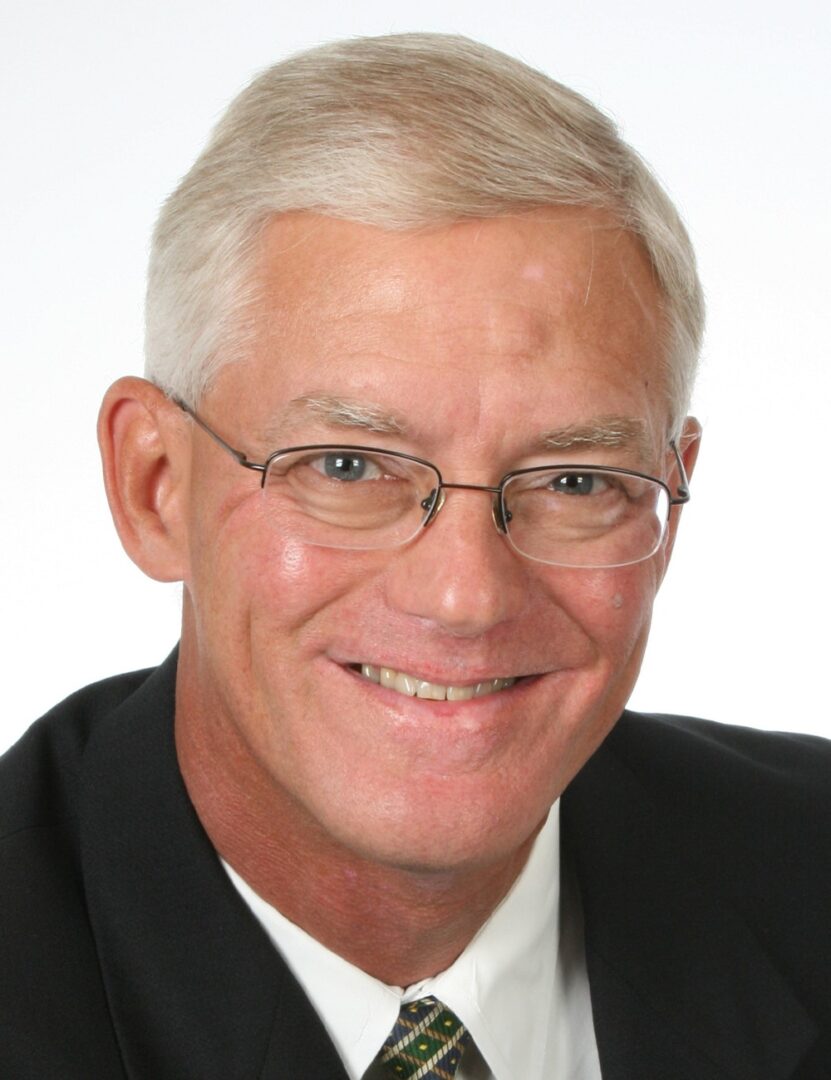 a man wearing a suit and glasses smiling for the camera